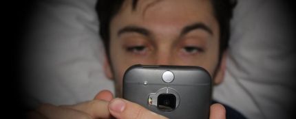 Hombre mirando el móvil en la cama