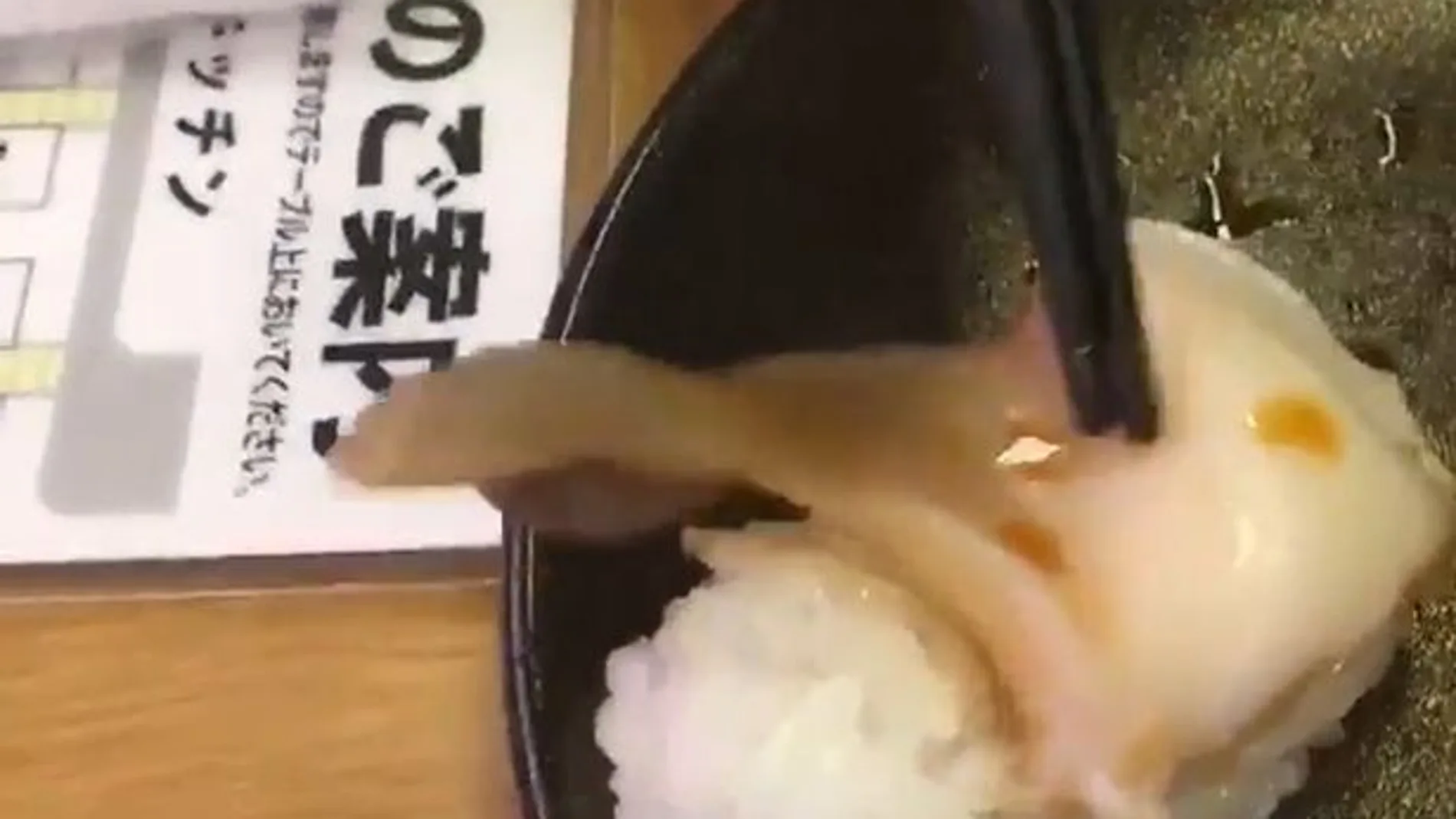 Un trozo de almeja en una pieza de sushi que se mueve Un trozo de almeja en una pieza de sushi que se mueve